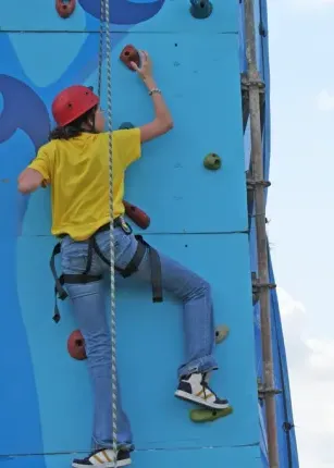 A student climbing an outdoor rock wall